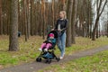 Young mother walks with a baby in a pram.