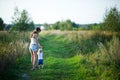 Young mother walks with her little daughter barefoot on a country road at sunset. The nanny walks with the child.