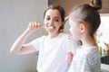 Young mother woman with long hair with little tween girl daughter in pajamas brushing their teeth in the morning at home Royalty Free Stock Photo