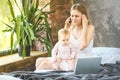 Young mother working from home, talking on smartphone while spending time with her baby girl. Freelance. Working home. Royalty Free Stock Photo