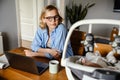 Young mother working with laptop while spending time with her baby Royalty Free Stock Photo