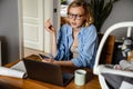 Young mother working with laptop while spending time with her baby Royalty Free Stock Photo