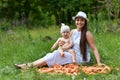 A young mother of 28 years old sits with her son in her arms on a pile of carrots in nature near a forest in a clearing and holds