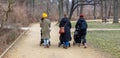 Young mothers with strollers walk in a city park in winter Royalty Free Stock Photo