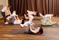 Young mothers and their babies doing yoga exercises on rugs at fitness studio.