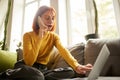 Young motivated woman using phone or laptop making online order, checking purchase, shopping at home, indoors. Startup Royalty Free Stock Photo