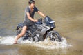 young motorcyclist rushes in the water in a spray at high speed