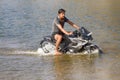 young motorcyclist rushes in the water in a spray at high speed