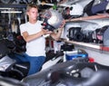 Young motorcyclist sitting and choosing helmet