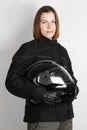 Young motorcyclist woman holding helmet in studio