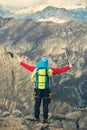 Young mountaineer standing with backpack on top of a mountain