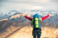 Young mountaineer standing with backpack on top of a mountain