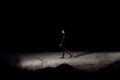 A young mulatto girl in a leather jacket and black clothes is walking along an abandoned sandy road with a bottle of whiskey. at Royalty Free Stock Photo