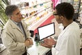 Young Mulatto male pharmacist speaking with a customer