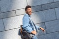 Freestyle. Mulatto guy carrying backpack walking isolated on wall laughing cheerful side view