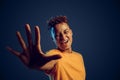 Freestyle. Mulatto guy standing isolated on dark red in yellow light giving five close-up blurred background laughing
