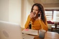 Young multi-cultural female blowing her nose while on a business call. Sick and working from home on laptop