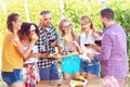 Young multi-ethnic friends having fun outdoor drinking red wine at open air bar-b-que party in countryside restaurant with Royalty Free Stock Photo