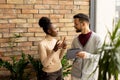 Young multiethnic business couple with digital tablet standing and discussing in the modern office Royalty Free Stock Photo