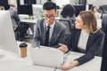 Young multiethnic businessman and businesswoman discussing work and pointing at laptop Royalty Free Stock Photo