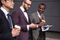 Young multiethnic businessmen in formalwear walking at coffee break outdoors