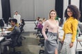 Young multiethnic businesswomen smiling at camera while colleagues working behind Royalty Free Stock Photo