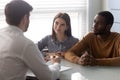 Young multiethnic couple consulting with male agent at office meeting