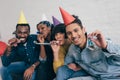 young multiethnic friends in party hats celebrating with party