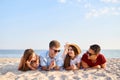 Young multiethnic group of people relaxing on the beach towel near the sea on white sand. Stylish friends hanging on the Royalty Free Stock Photo