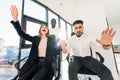 Young multiracial business people staged crazy office games on chairs.