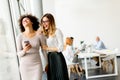 Young multiracial businesswomen smiling, while other businesspeople working in background