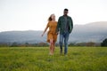 Young multiracial couple smiling and holding hands while walking in field Royalty Free Stock Photo