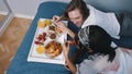 Young multiracial couple eating breakfast in bed. Woman taking strawberry from her boyfriend. slow motion