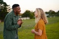 Young multiracial couple face to face shouting and gesturing in field