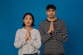 Young multiracial couple frowning and making pray gesture