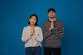 Young multiracial couple frowning and making pray gesture