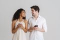 Young multiracial couple laughing while using mobile phones Royalty Free Stock Photo