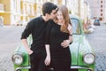 Young multiracial couple, male and female lovers heterosexual people students. Beautiful models posing standing near a retro car