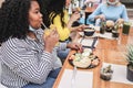 Young multiracial friends having breakfast in restaurant outdoors with masks under chins - Focus on african girl Royalty Free Stock Photo