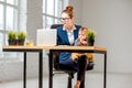 Multitasking businesswoman with her son working at the office Royalty Free Stock Photo