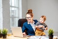 Multitasking businesswoman with her son working at the office Royalty Free Stock Photo