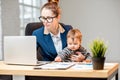 Multitasking businesswoman with her son working at the office Royalty Free Stock Photo