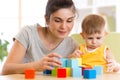 Young mummy and her kid play with cubes toys in nursery Royalty Free Stock Photo