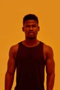 Young muscular african american man looking at camera, posing isolated over orange background. Sports, workout Royalty Free Stock Photo