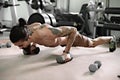 Young muscular athlete doing pushups in gym.