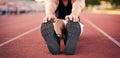 Young muscular athletic runner man stretching and touching his feet on a running court in sitting position before starting of Royalty Free Stock Photo