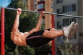 Young muscular build man doing pull ups exercises on horizontal bar outdoors. Royalty Free Stock Photo