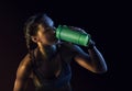 Young muscular build woman silhouette drinking water of bottle. Royalty Free Stock Photo