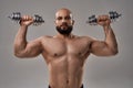 Young muscular caucasian athlete lifting dumbbells