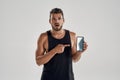 Young muscular caucasian athlete pointing into smartphone screen